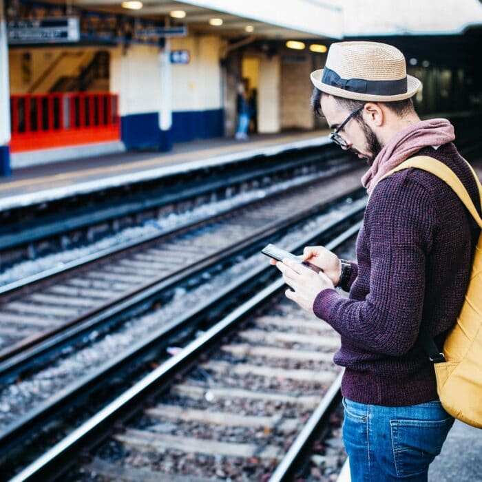 man on phone while standing at train station