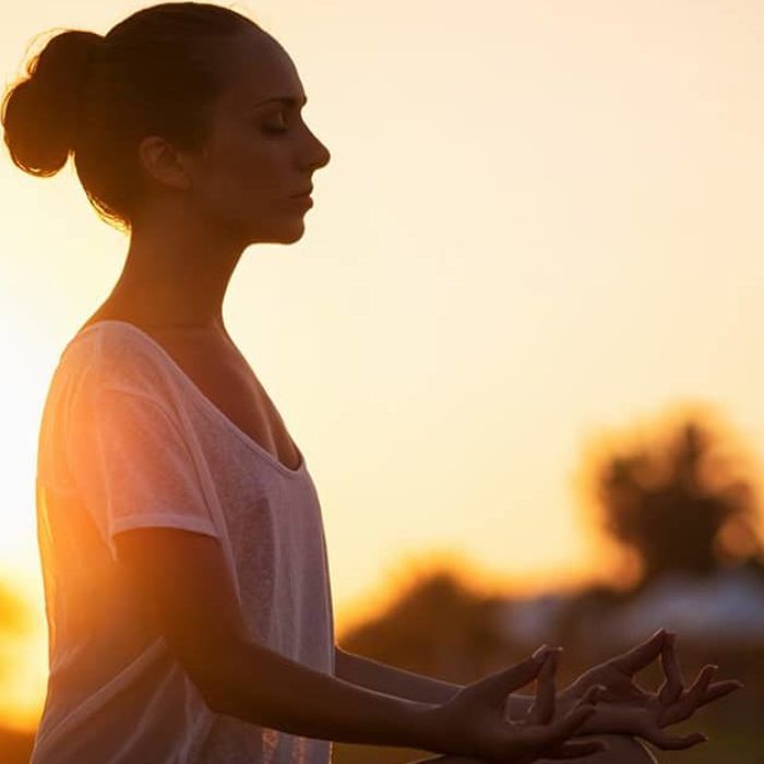 woman doing yoga meditation at sunset