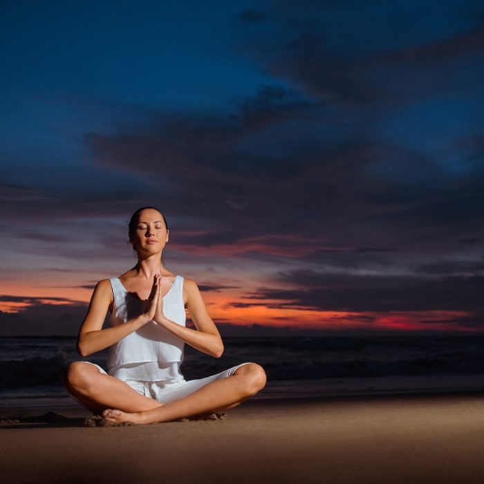 Woman Meditating At Sunset