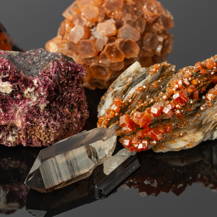 Close up photo of the Group of Stones and Minerals including Vanadinite on Barite, Aragonite Sputnik, Erythrite Crystals on Reflective Surface