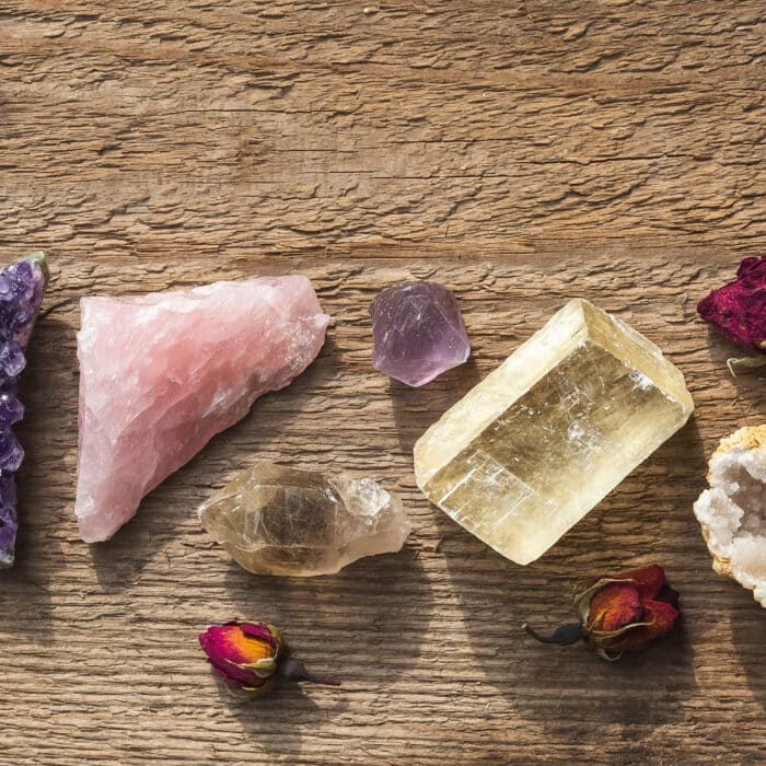Amethyst druzy, pink quartz, quartz with rutile, fluorite, calcite, quartz in geode mineral stones set up on the wooden table with dry flowers. Gemstones for esoteric spiritual practice or witchcraft