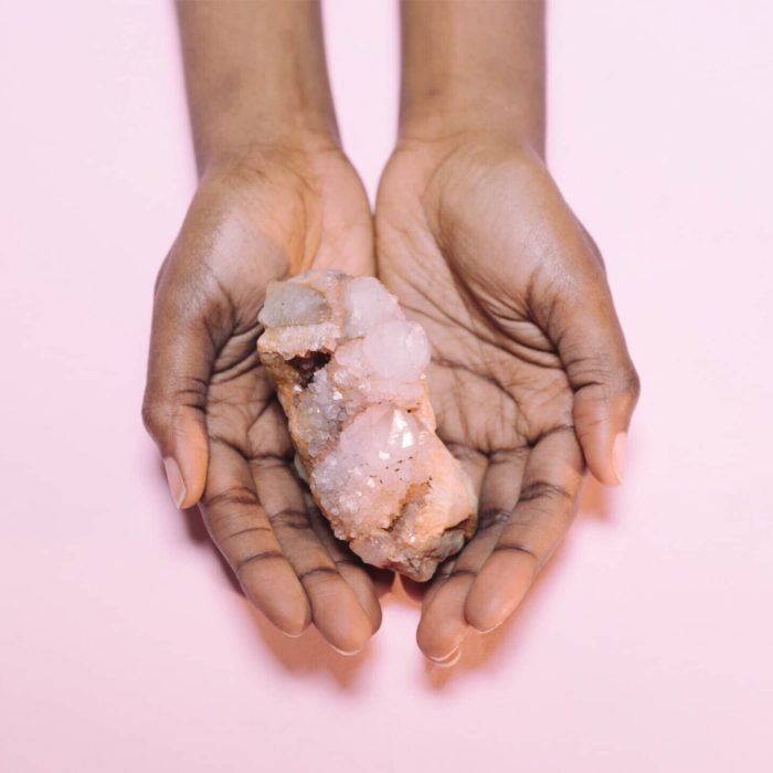 person holding pink crystal on palms