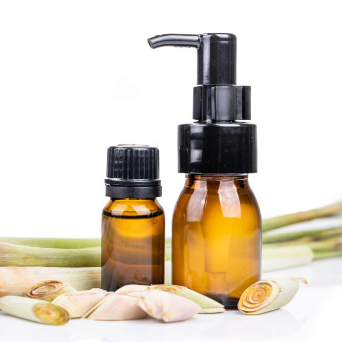 Lemongrass essential oil extract in bottle with fresh lemongrass plant in white background