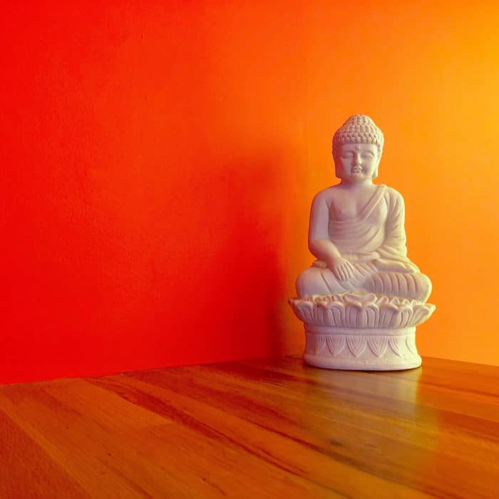 white buddha statue with red orange background