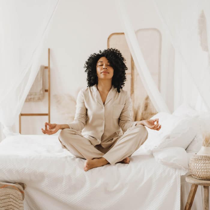 young woman practicing meditation on the bed
