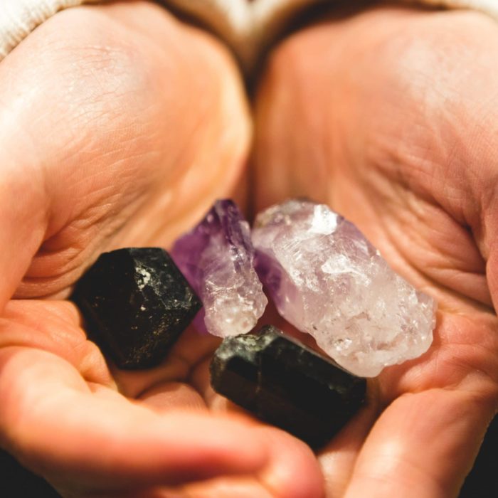 hands holding different crystals and quartz