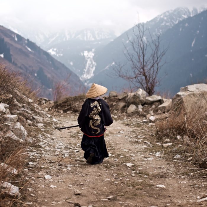 rearview of a young boy dressed like a samurai walking on the mountain road