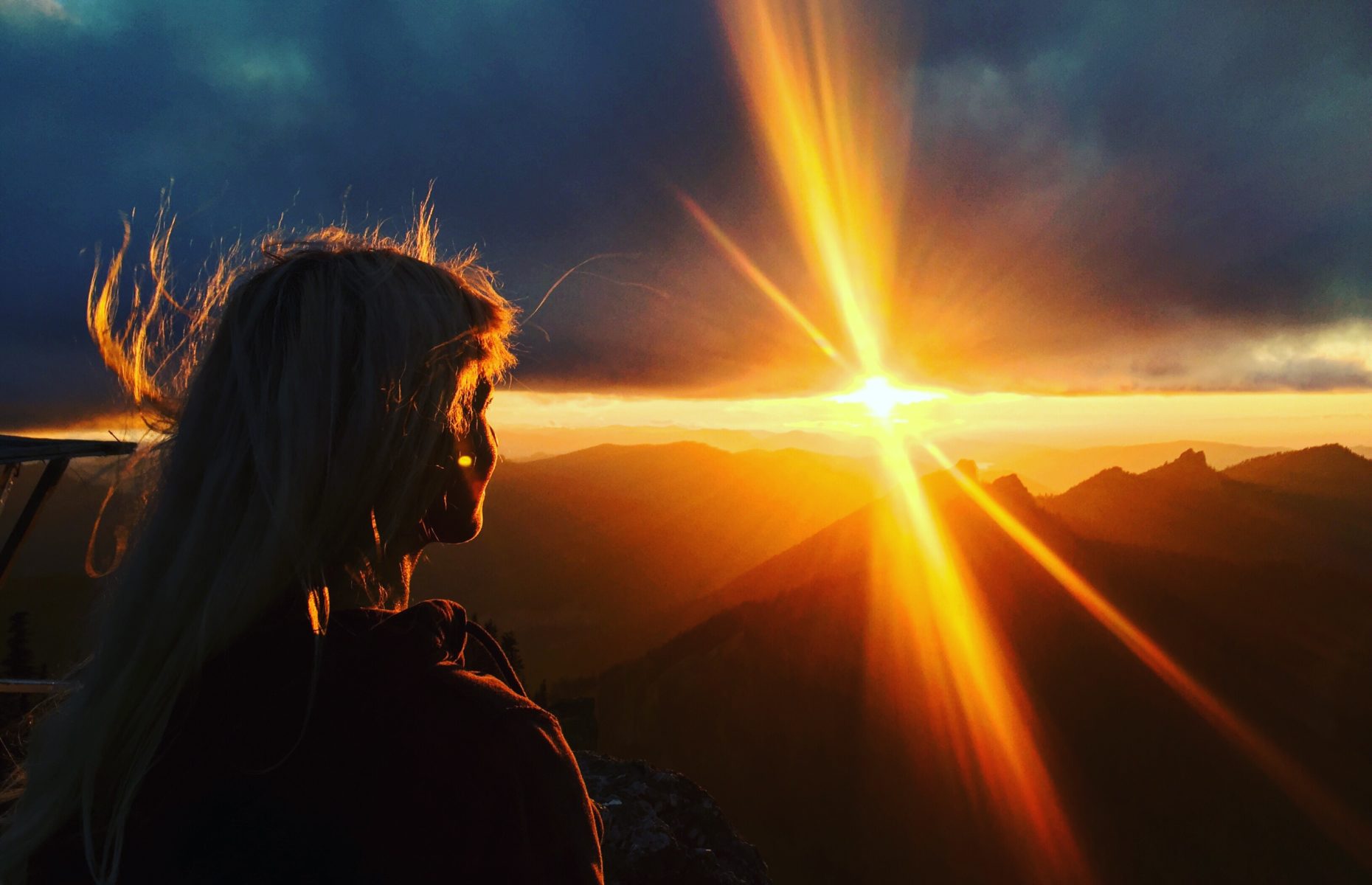 woman on top of a mountain looking at sunset