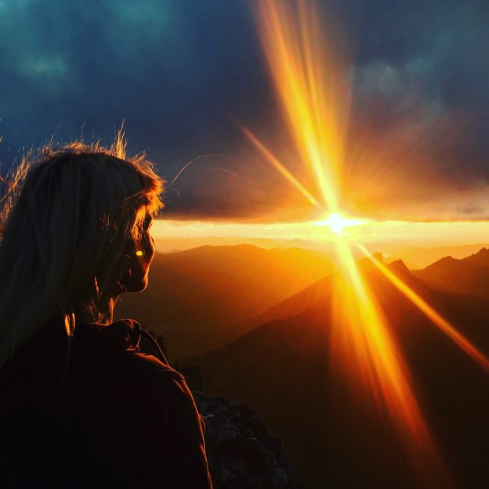 woman on top of a mountain looking at sunset