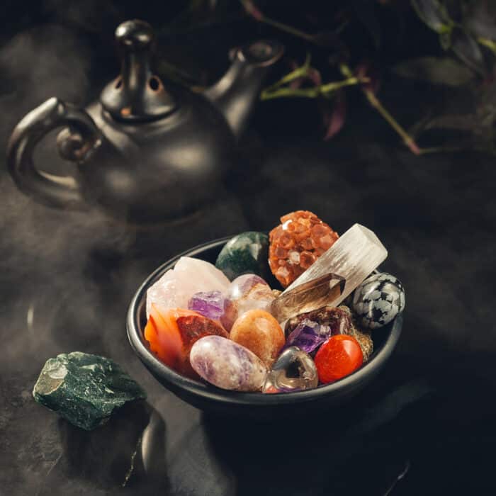 Bunch of Colorful Crystals and Rough Mineral Stones in the Black Bowl Shrouded in a Mystical Mist. Crystal Cleansing Fumigation. Copy Space for Text
