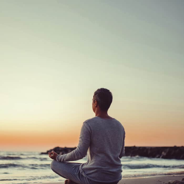 Man meditating during sunset near the sea beach