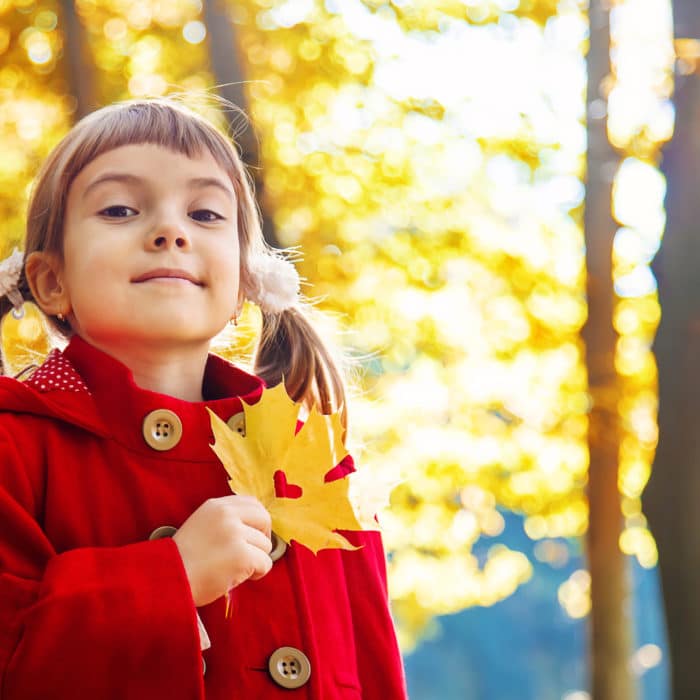 child in a red coat with autumn leaves. Love autumn. Selective focus.