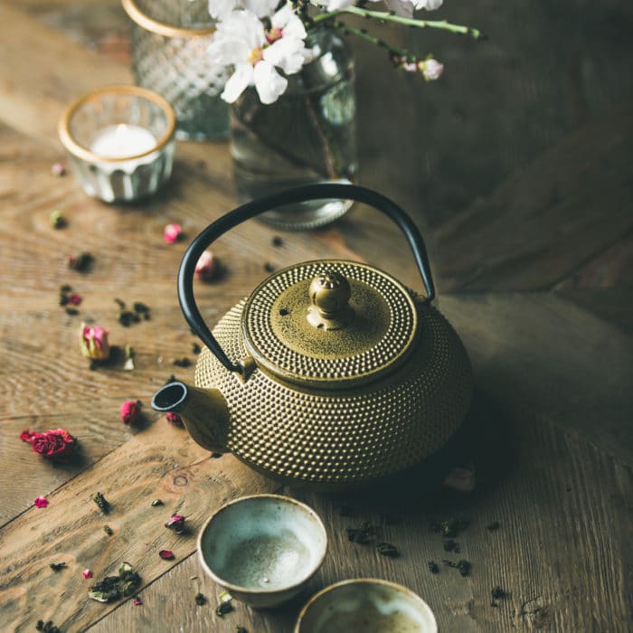 Golden iron teapot, cups, dried rose, candles, almond flowers