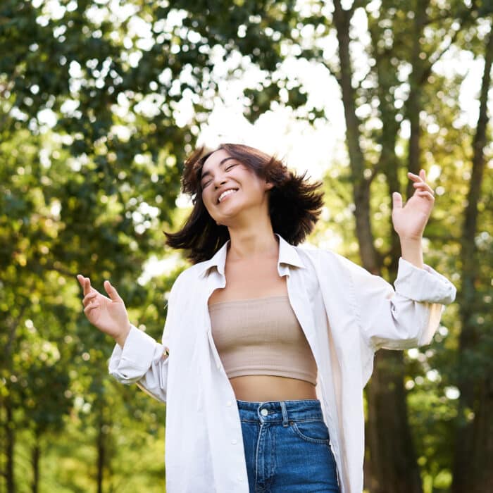 Happy people. Carefree asian girl dancing and enjoying the walk in park, feeling happiness and joy, triumphing