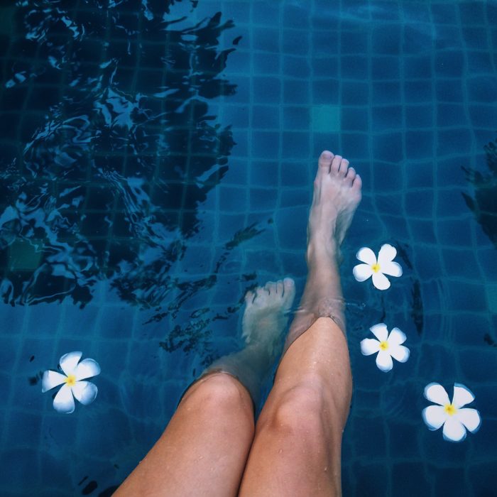 woman dipping feet in pool with flowers