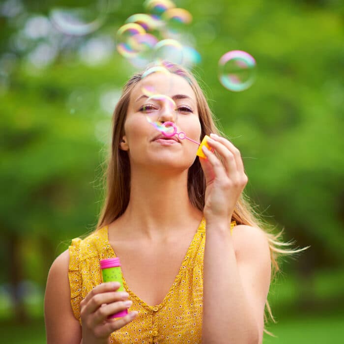 Indulging her inner child. Shot of a carefree young woman blowing bubbles in the park