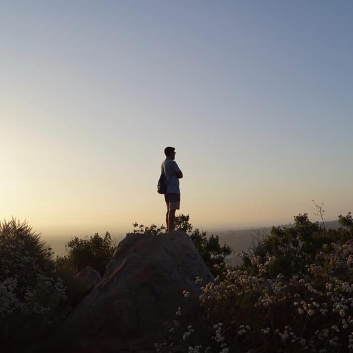 Man standing atop a rock sunset sunrise meditating reflecting