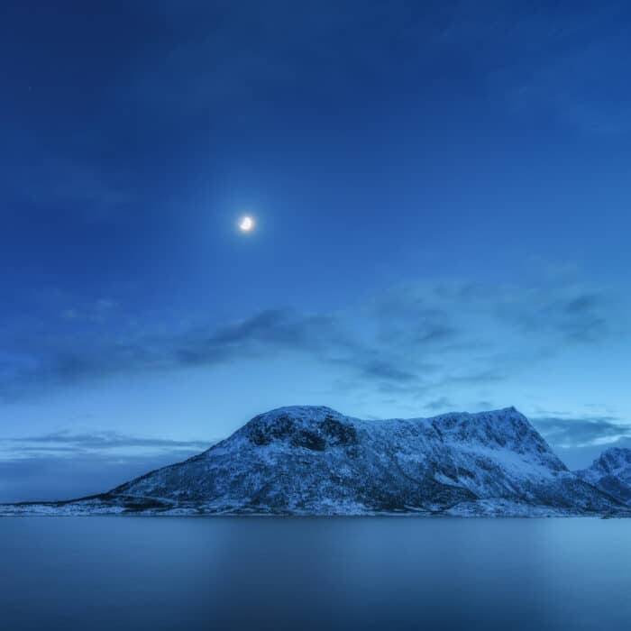 Mountains against blue sky with clouds and moon in winter