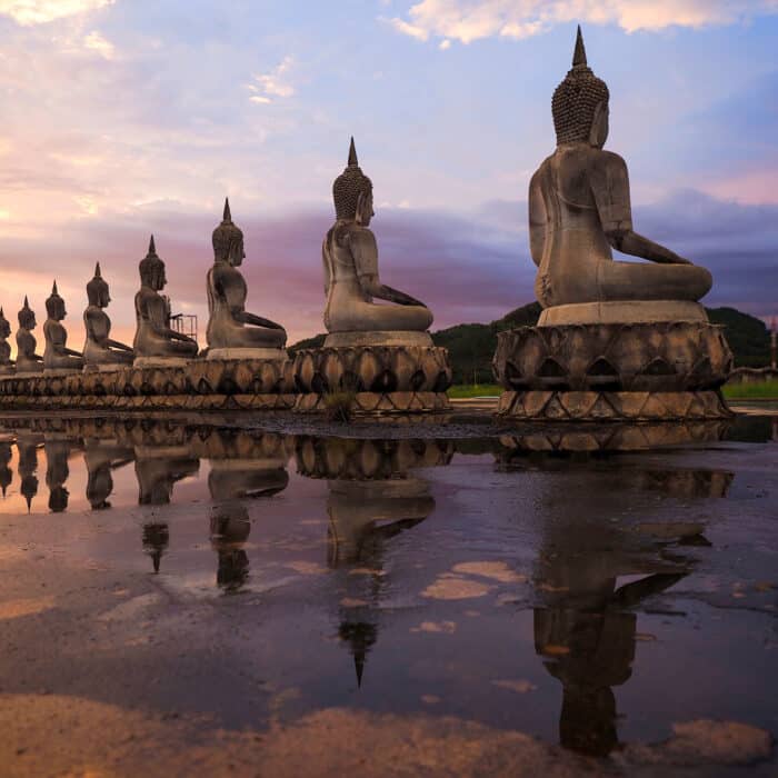 Row of Buddha statues on a sunset background
