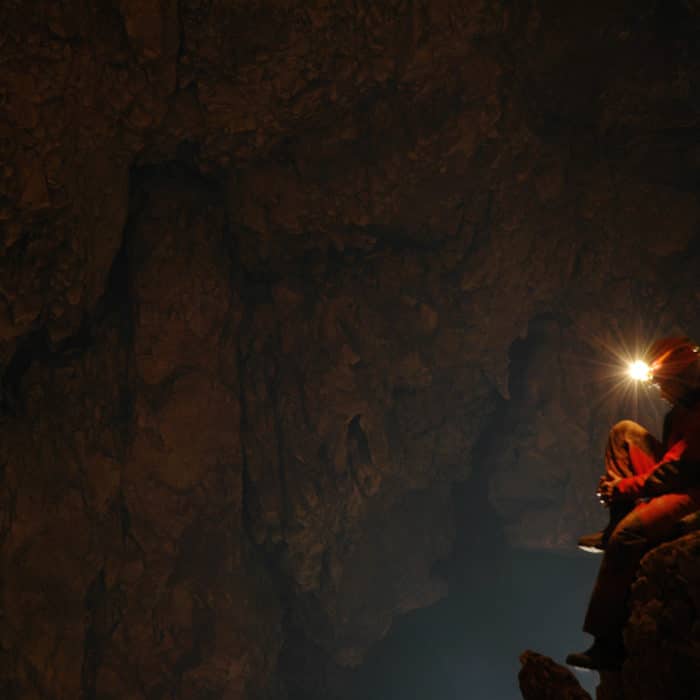 guy using flashlight inside cave
