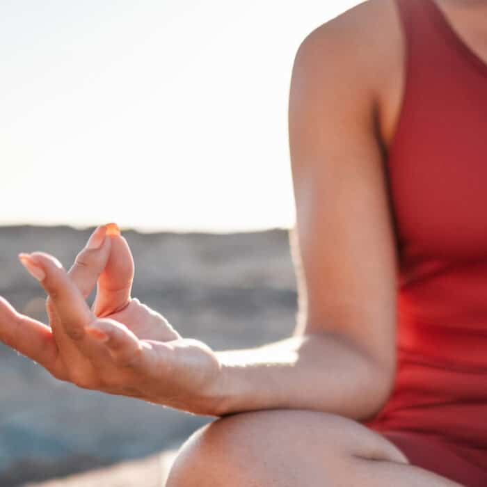 Woman, hands and meditation in yoga at beach for spiritual wellness or peaceful exercise in nature