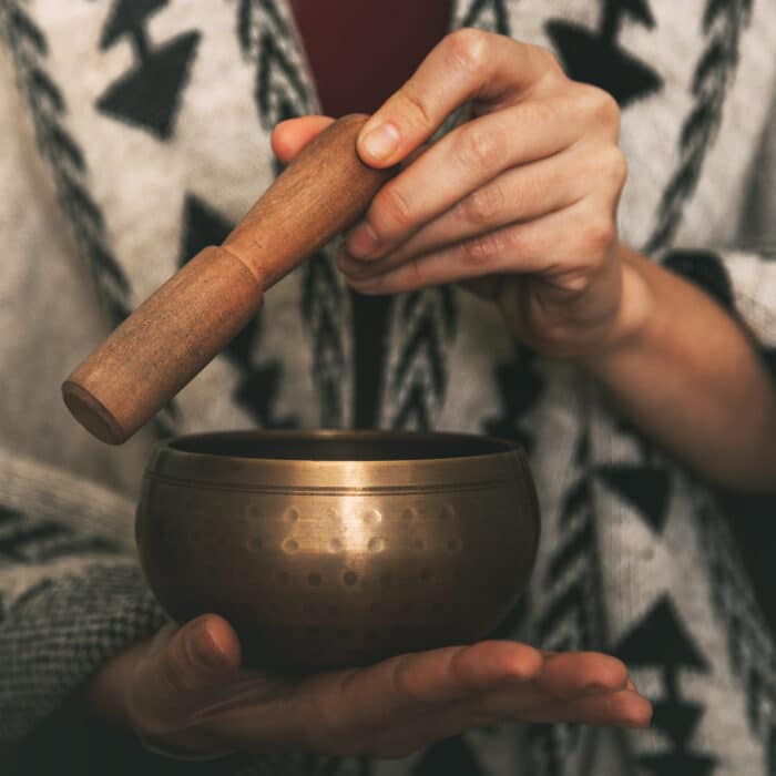 Hands of a woman using a golden Tibetan bowl