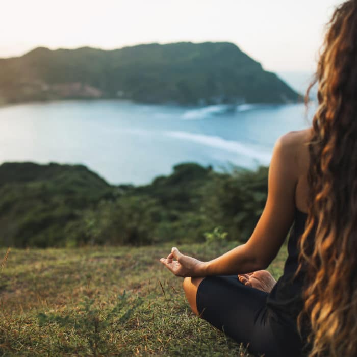Woman meditating yoga alone at sunrise mountains