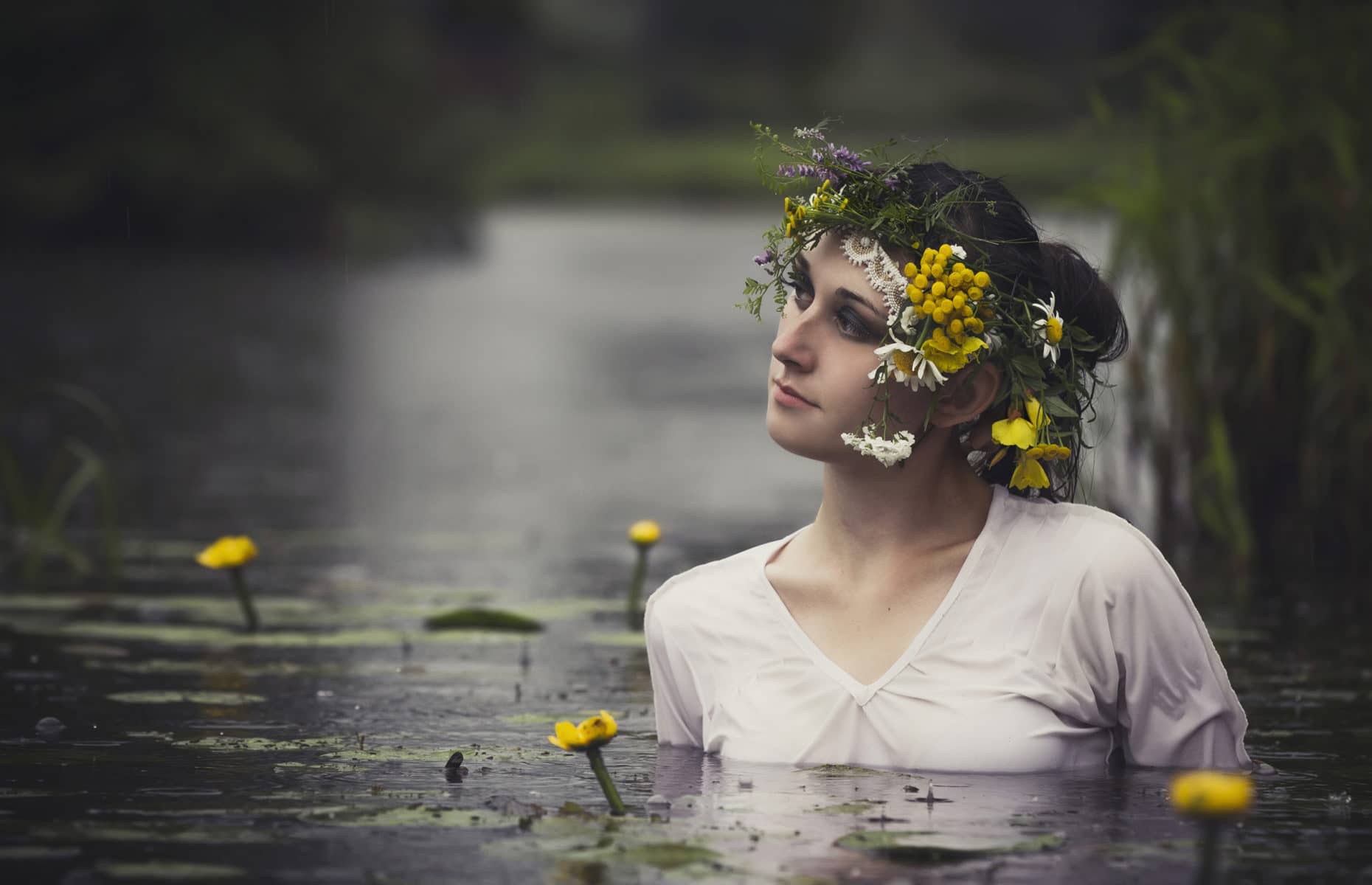 Art Woman with wreath on her head in a swamp in the woods. Wet witch Girl in the lake, mystical mysterious woman bathing outdoors in the swamp. Wreath of wildflowers on her head