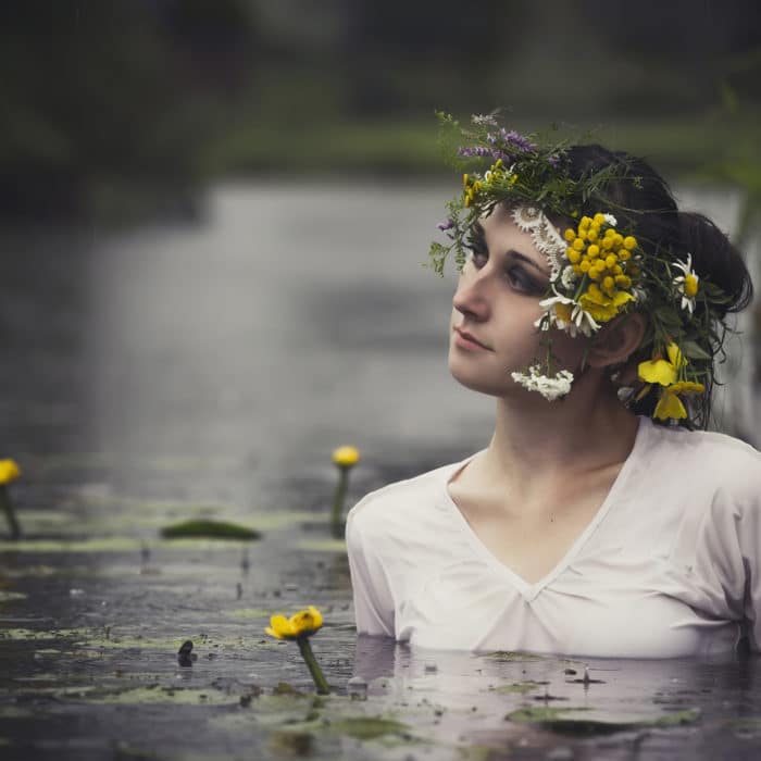 Art Woman with wreath on her head in a swamp in the woods. Wet witch Girl in the lake, mystical mysterious woman bathing outdoors in the swamp. Wreath of wildflowers on her head