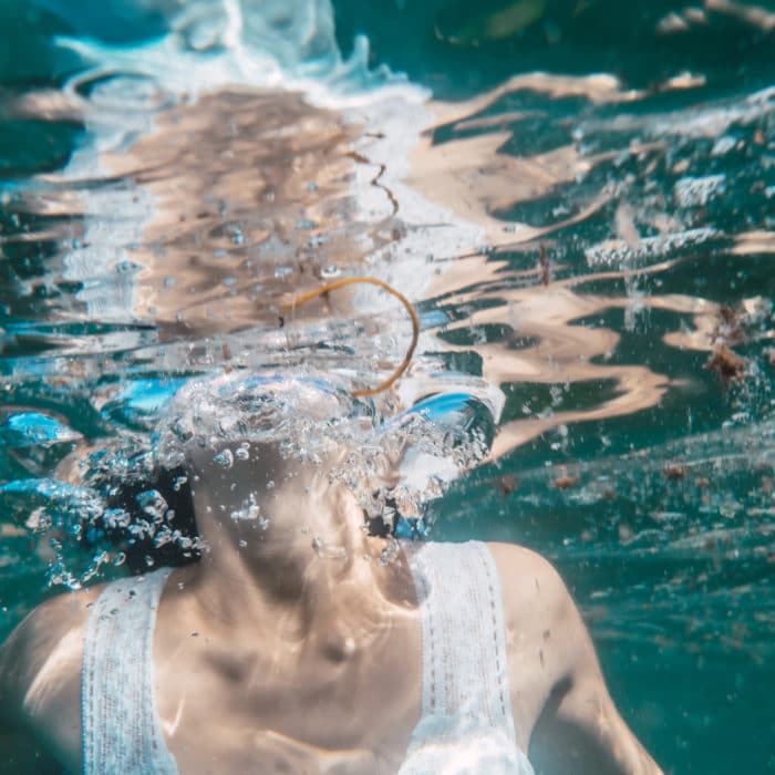 A young woman will dive with a white dress swimming, underwater image, summer
