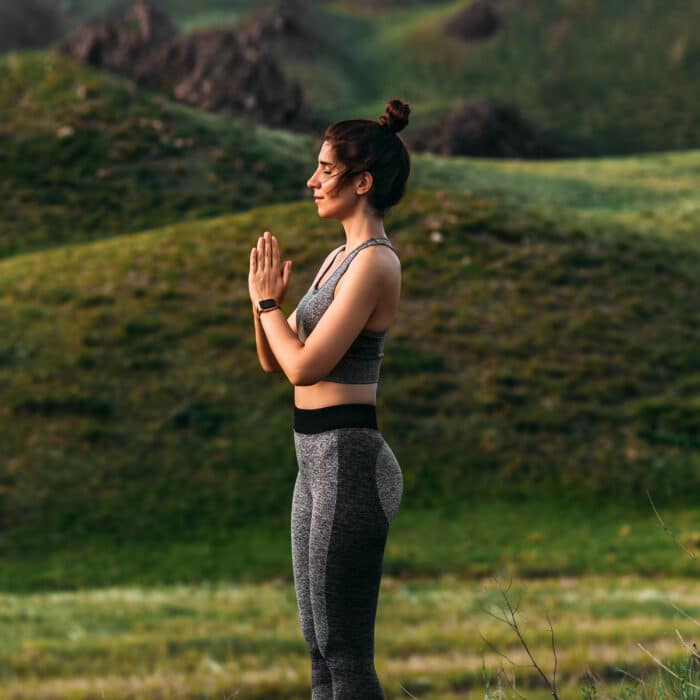 An attractive and healthy young woman does yoga in the mountains at sunset. Yoga in the fresh air. Happy woman doing yoga exercises. Meditation in nature. A woman practicing yoga in the mountains
