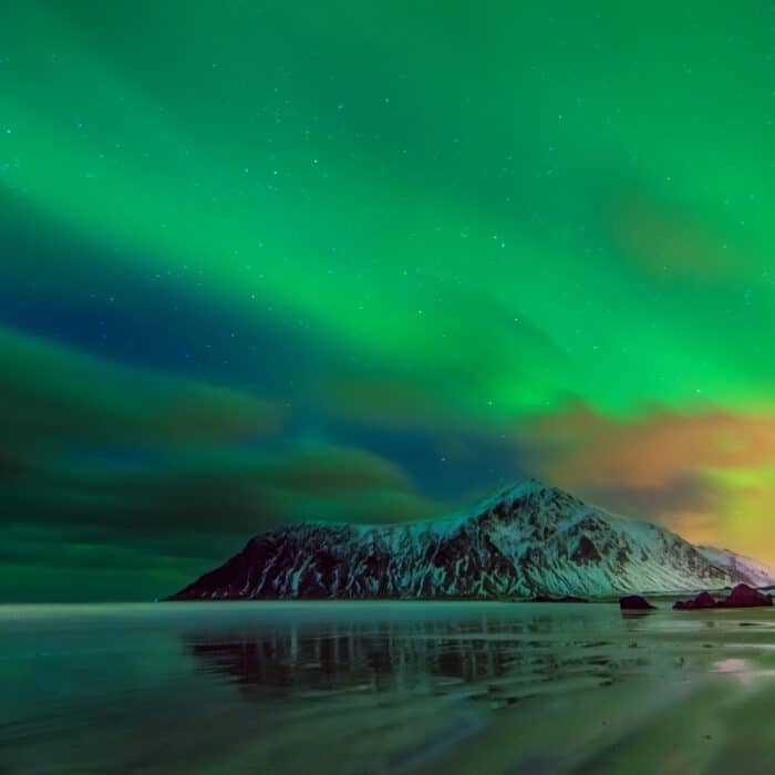 Aurora borealis over snowy islands from Uttakleiv beach of Lofot