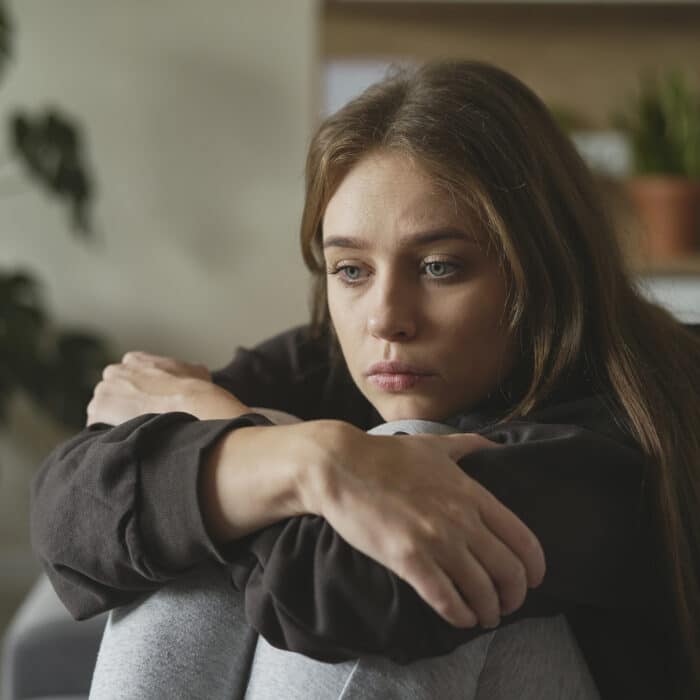 Caucasian sad woman sitting at the sofa with depression