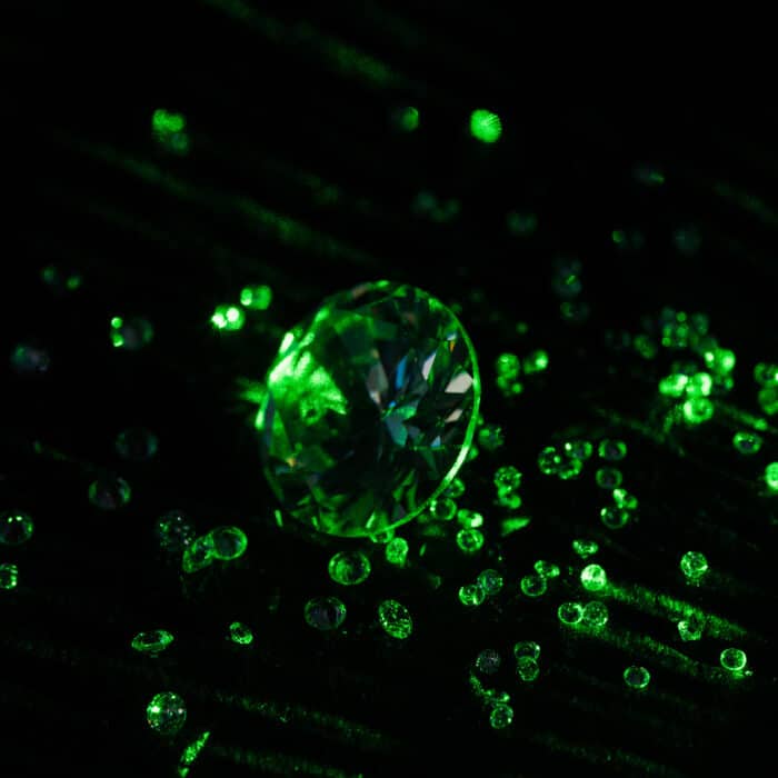 Collection of diamonds with bright green neon light on dark background