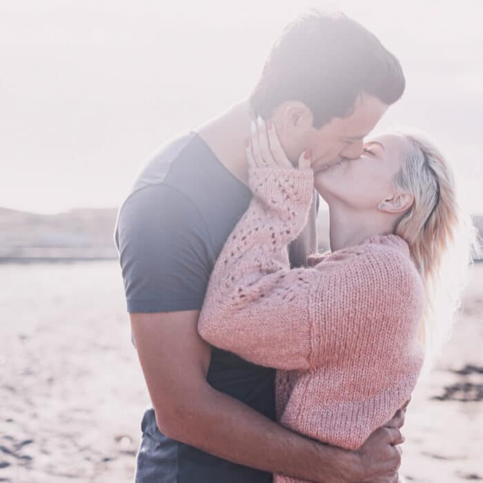 Couple kissing outdoor with love in relationship. Dating and vacation together concept. Young girl and man in romantic kiss under the sun. Two people couple embracing at the beach in summer vacation