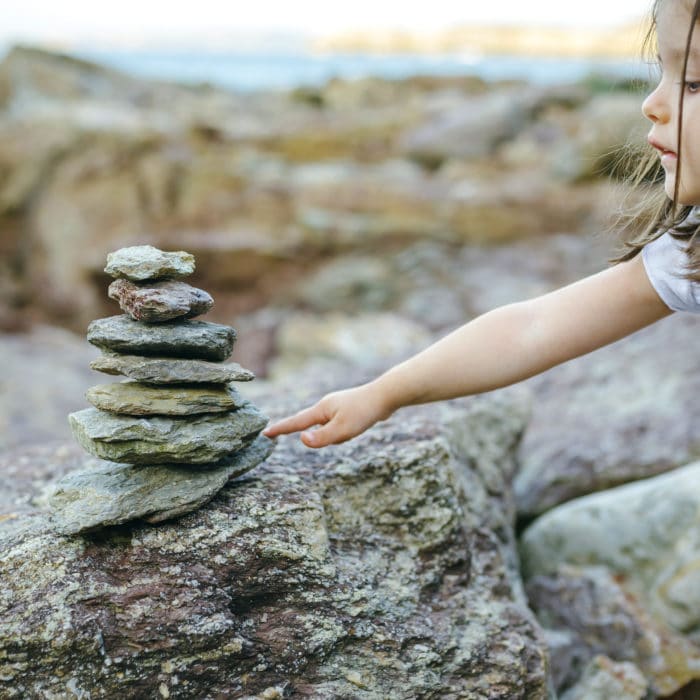 Girl with stack of stones at rocky coast