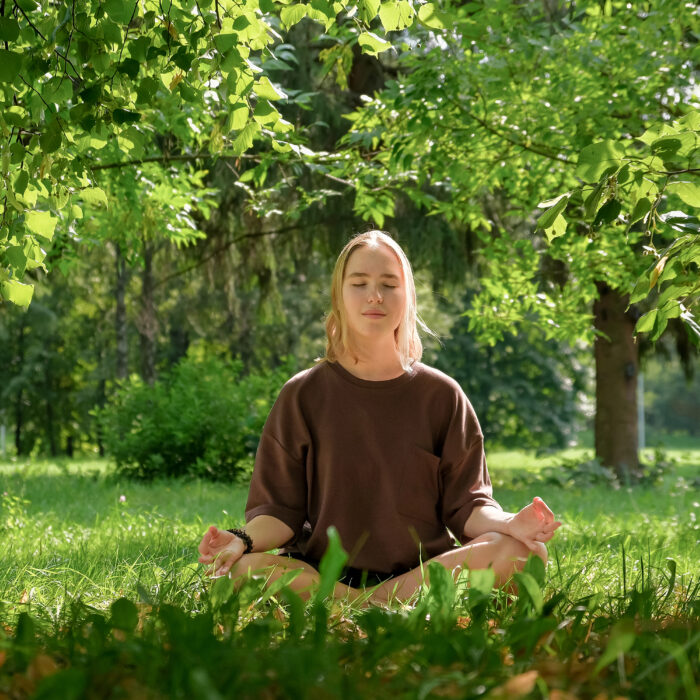 Meditation Woman meditates in nature outdoor.At ground level, a relaxed woman meditates and breathes while sitting in Lotus pose next to fragrant incense during a yoga class in the garden