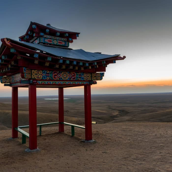 Pagoda for meditation or gazebo in Buddhist style in steppe with cloudless sky