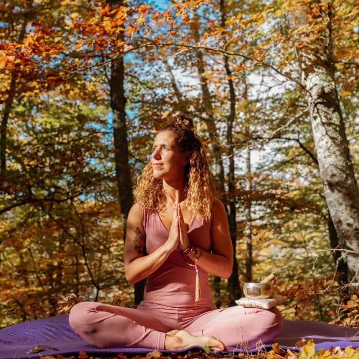 Woman doing meditation in the forest during autumn.