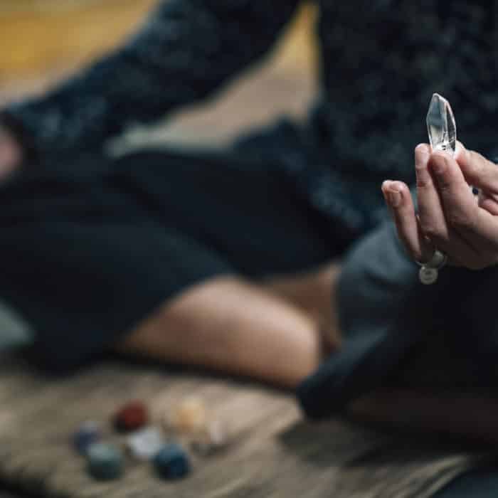 Woman Meditating with Quartz Crystal Chakra Wand in Hand