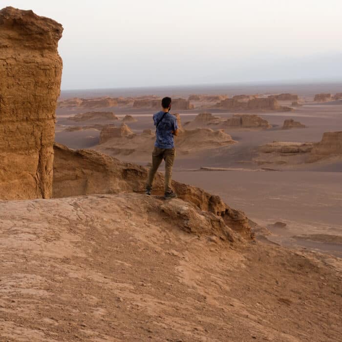 A young man looking at the breathtaking view of Lut desert in Iran