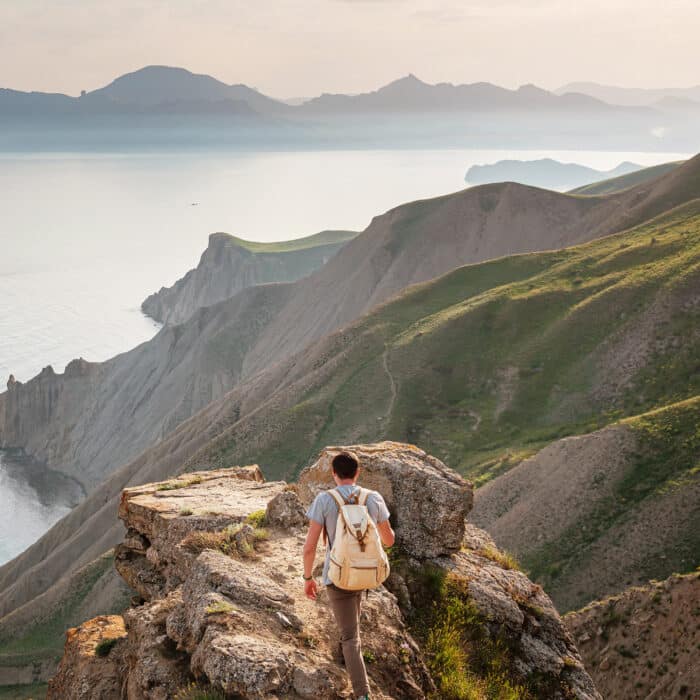 Young man travels alone on the backdrop of the mountains enjoy view of beautiful landscape natural mountain with sea, the lifestyle concept of traveling outdoors.