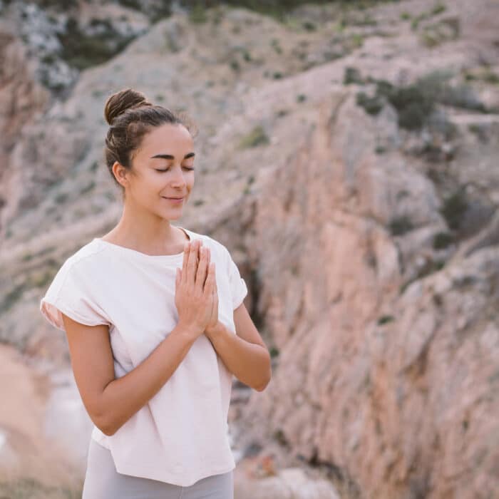 Young woman doing yoga exercises on mountain with beautiful sea
