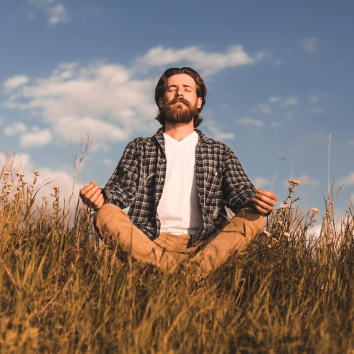 Bearded man meditating in field