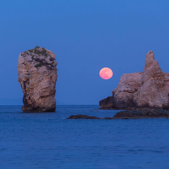 Full moon rise over the sea with rocks