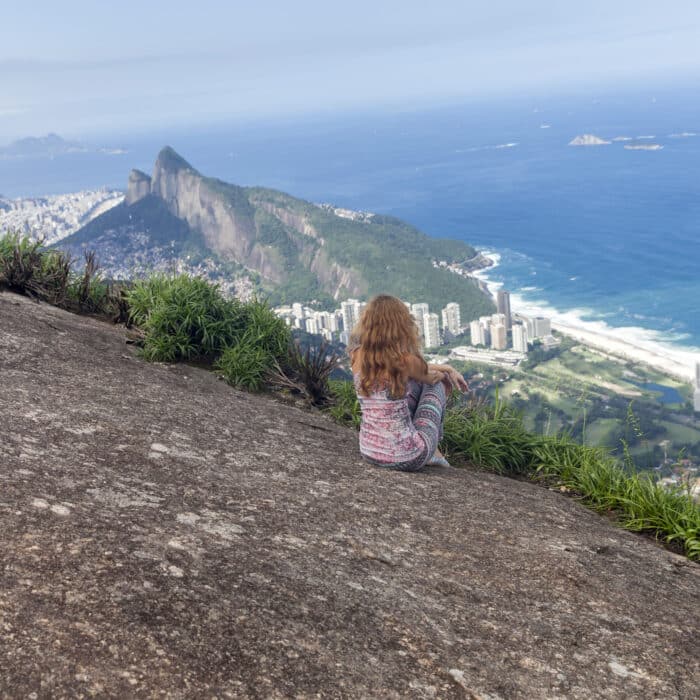Girl sitting at the edge of a mountain ni Rio de Janeiro, Brazil