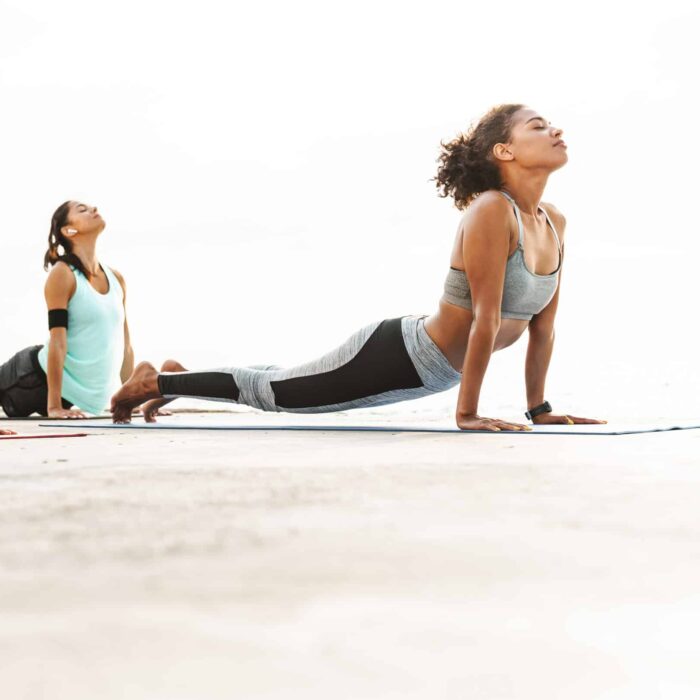 Three healthy fitness women doing yoga exercises on fitness mats