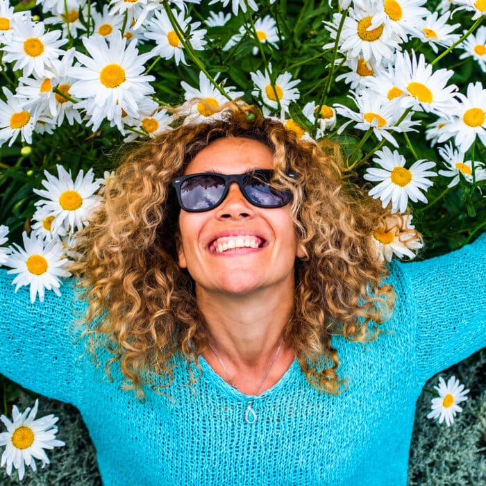People and happiness concept lifestyle with happu and cheerful adult beautiful caucasian young woman smile with green and coloured daisies background - leisure activity and park outdoor