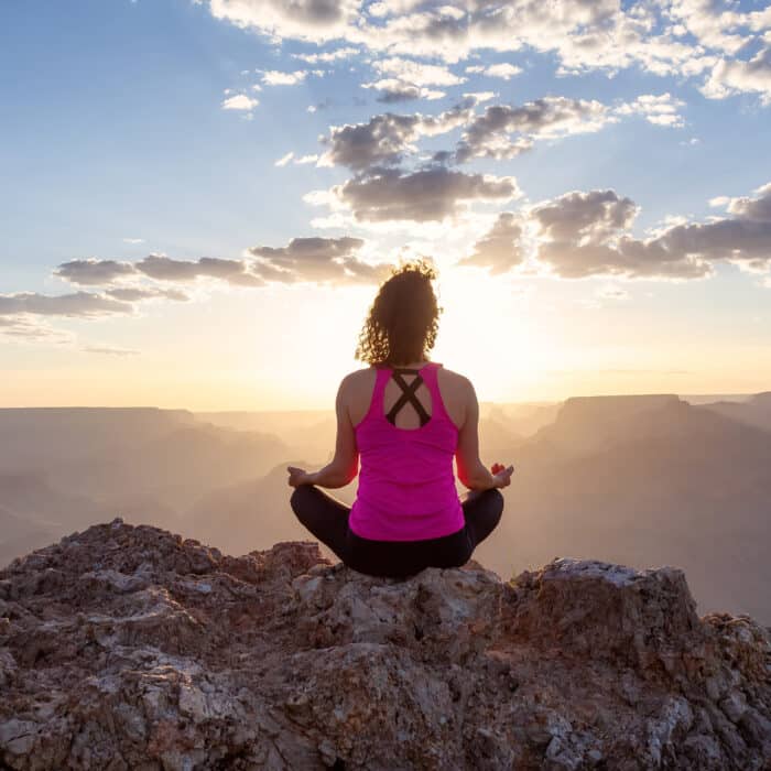 Adventurous Traveler woman doing meditation on Desert Rocky Mountain American Landscape.