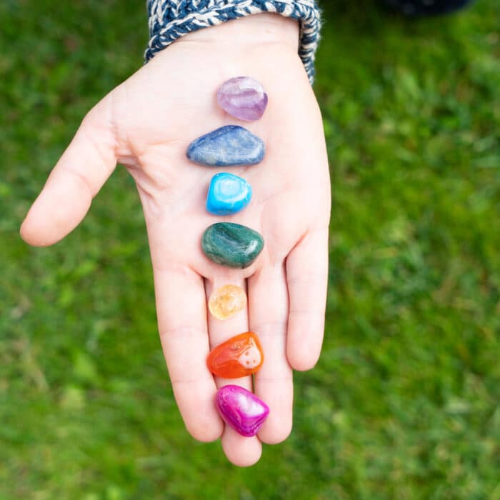 Someones hand holding set of chakra stones. Magic healing Rock for Reiki Crystal Ritual, Witchcraft, spiritual esoteric practice